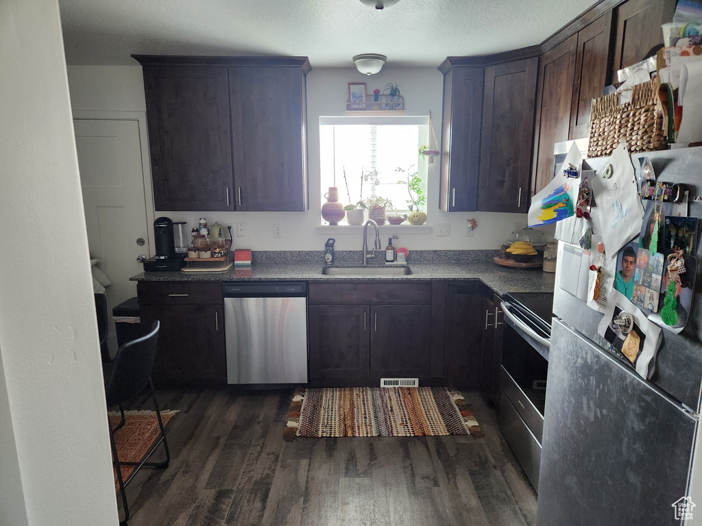 Kitchen featuring dark wood-type flooring, dark brown cabinetry, sink, a textured ceiling, and stainless steel appliances