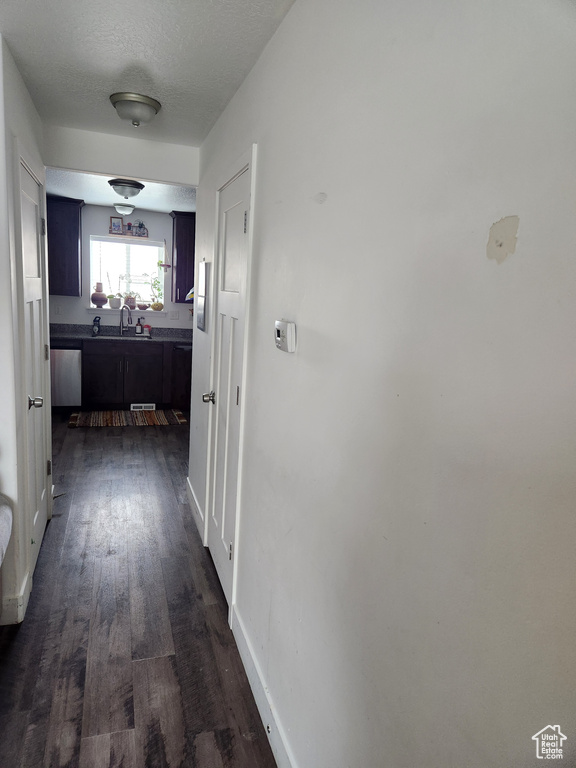 Corridor with dark wood-type flooring, sink, and a textured ceiling