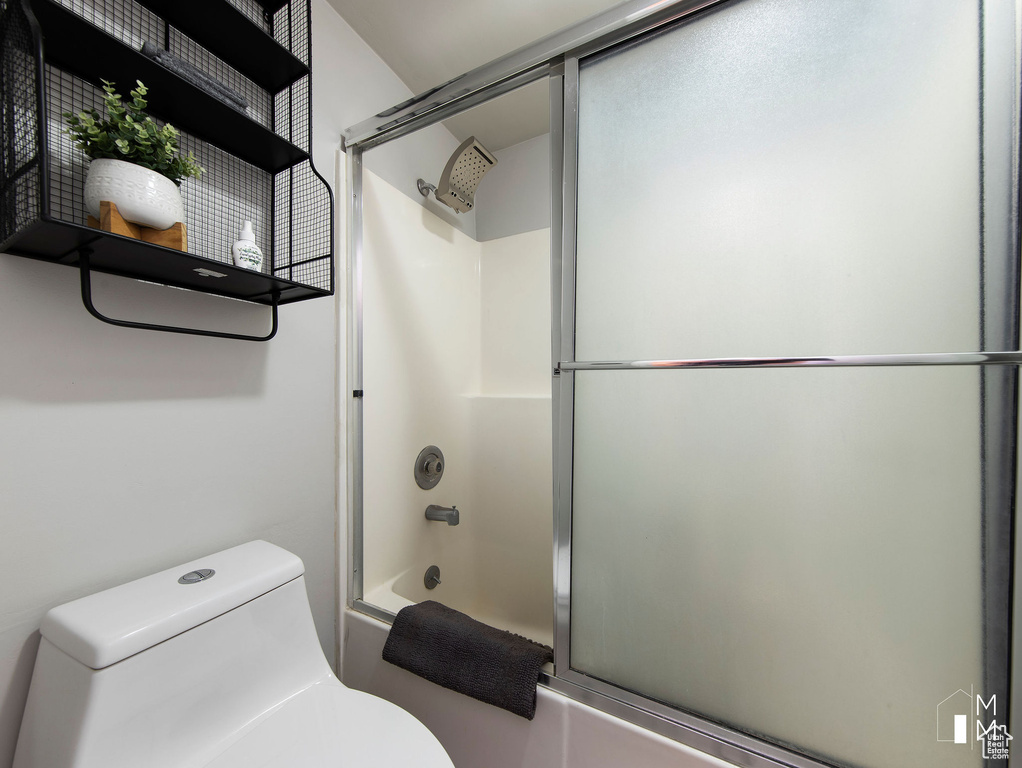 Bathroom with bath / shower combo with glass door and toilet