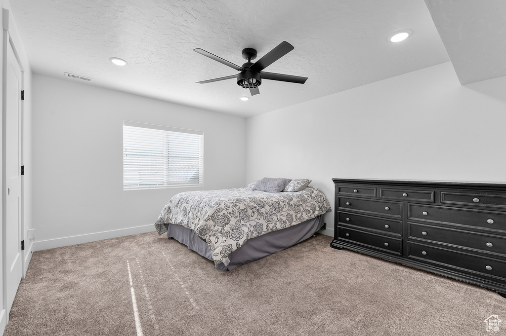 Carpeted bedroom with a textured ceiling and ceiling fan