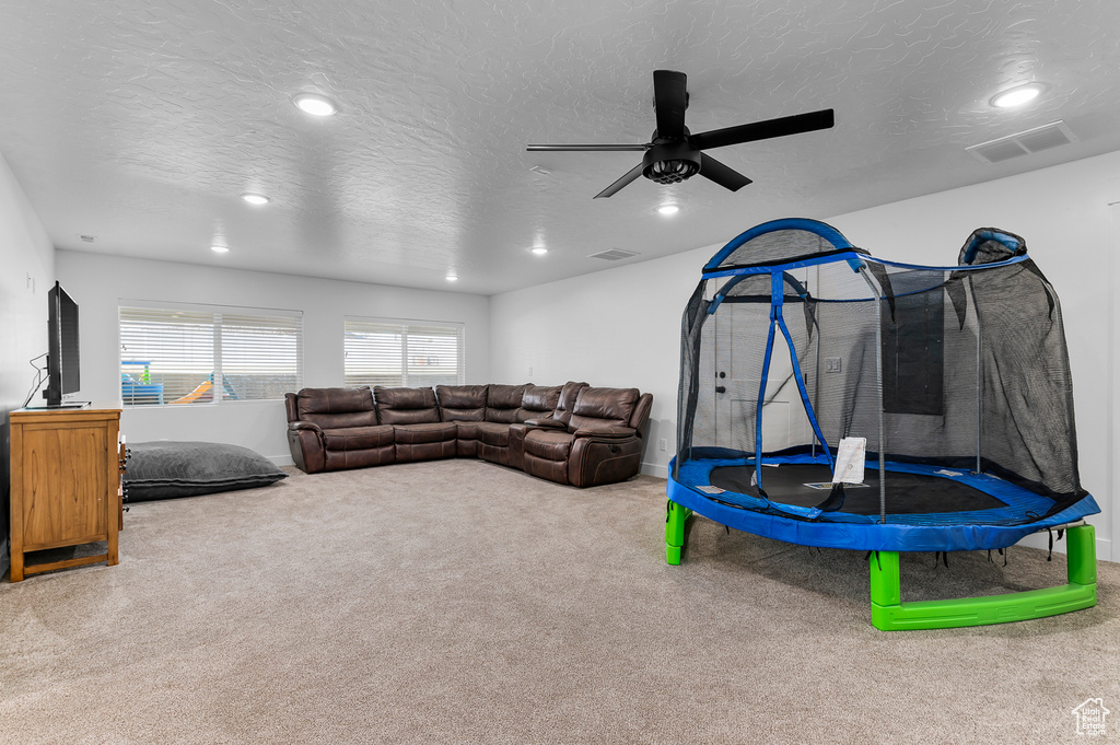 Living room featuring ceiling fan, carpet, and a textured ceiling