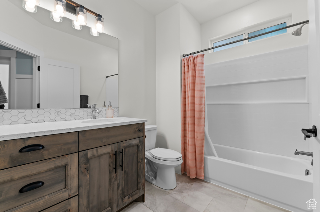 Full bathroom featuring tile patterned floors, toilet, tasteful backsplash, vanity, and shower / bath combo with shower curtain