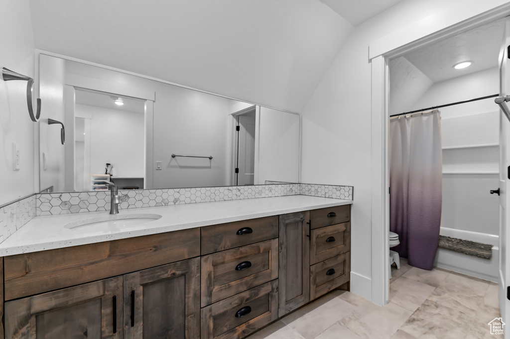 Full bathroom with shower / tub combo, backsplash, vanity, vaulted ceiling, and toilet