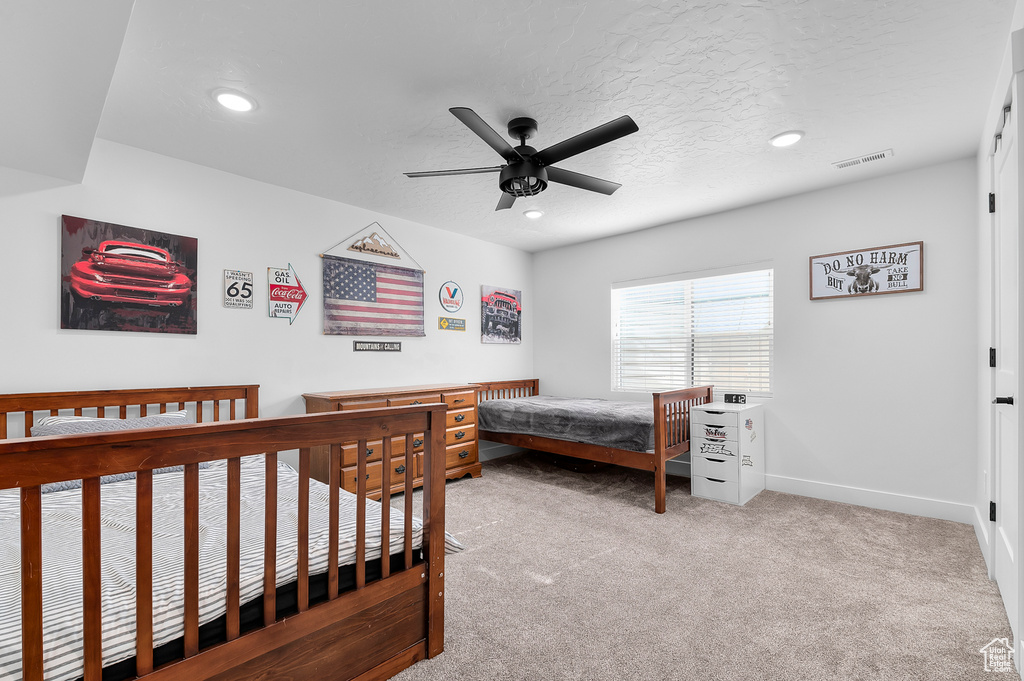 Carpeted bedroom with ceiling fan and a textured ceiling