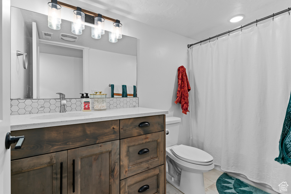 Bathroom with vanity, backsplash, tile patterned flooring, and toilet