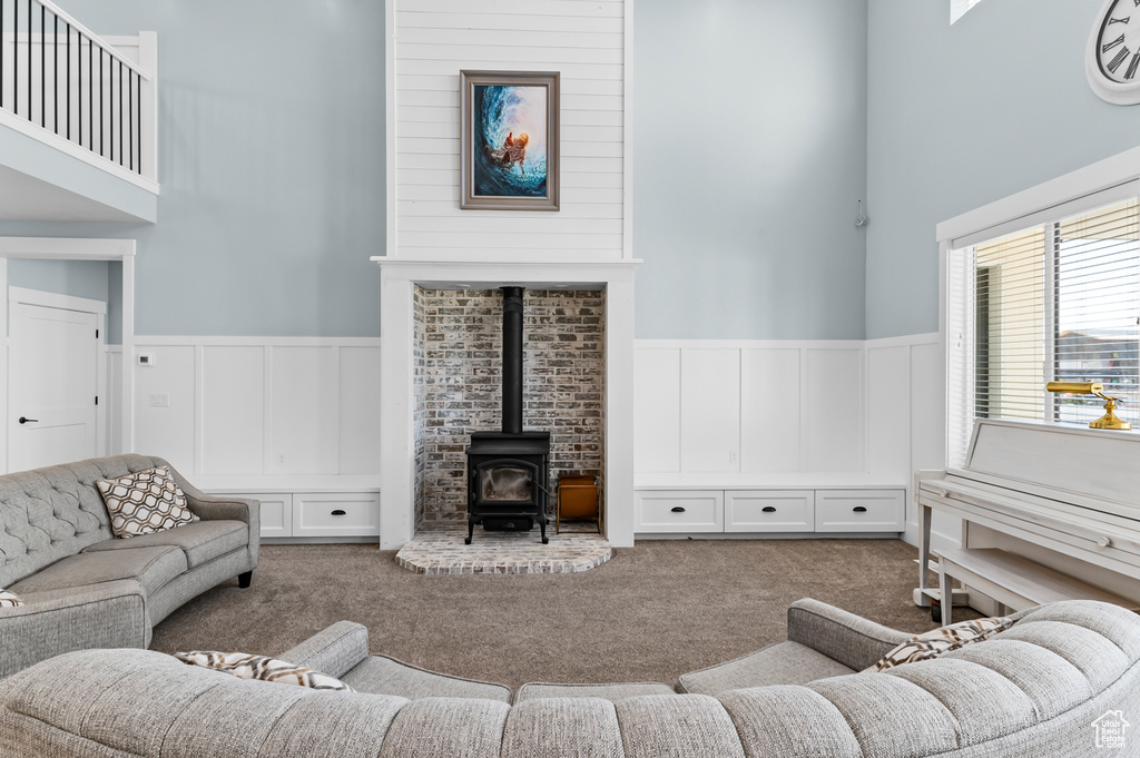 Living room with a wood stove, a high ceiling, and carpet