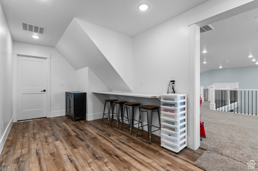 Bar with hardwood / wood-style flooring and lofted ceiling