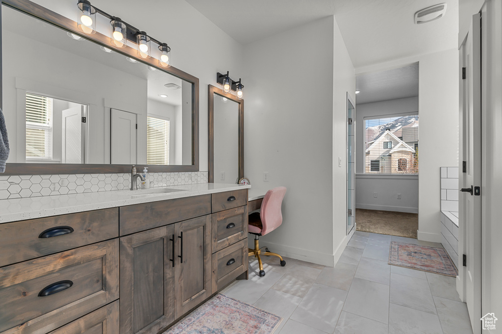 Bathroom featuring vanity, backsplash, and tile patterned floors