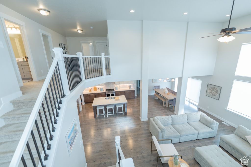 Living room featuring wood finished floors, a ceiling fan, recessed lighting, baseboards, and a towering ceiling