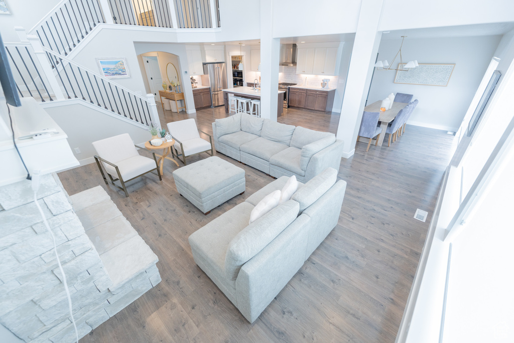 Living area with arched walkways, stairway, light wood-style flooring, a high ceiling, and baseboards