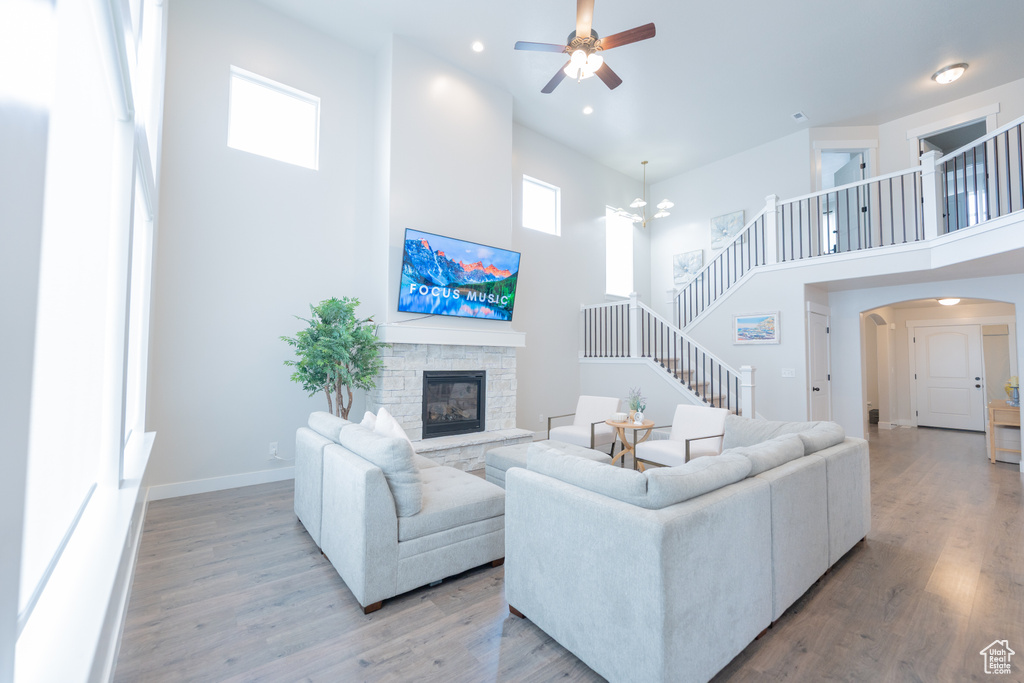 Living area featuring a towering ceiling, a ceiling fan, a fireplace, arched walkways, and plenty of natural light