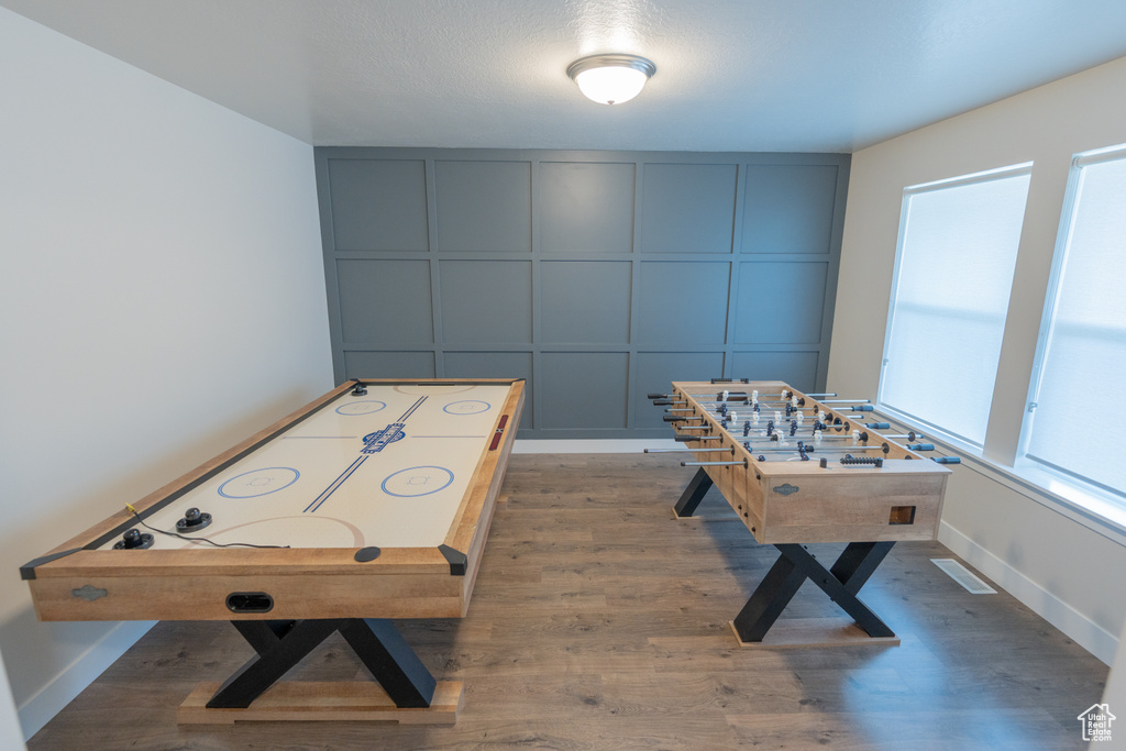 Game room featuring a decorative wall, wood finished floors, and baseboards