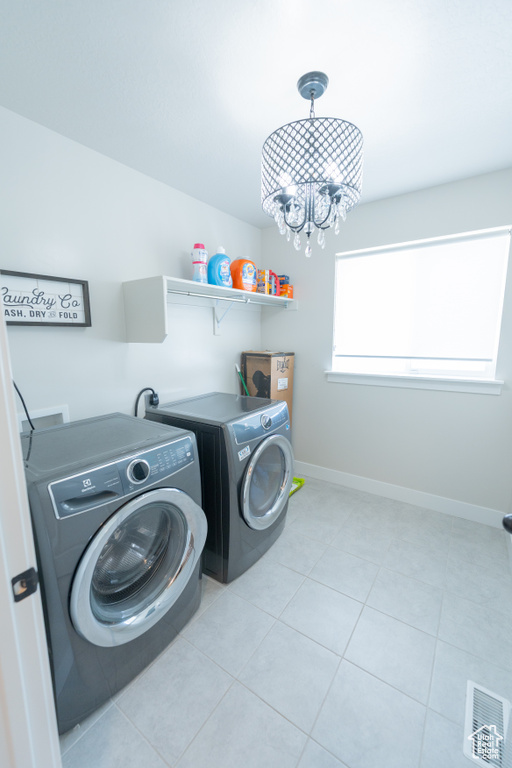 Washroom with independent washer and dryer, light tile patterned floors, a chandelier, and baseboards