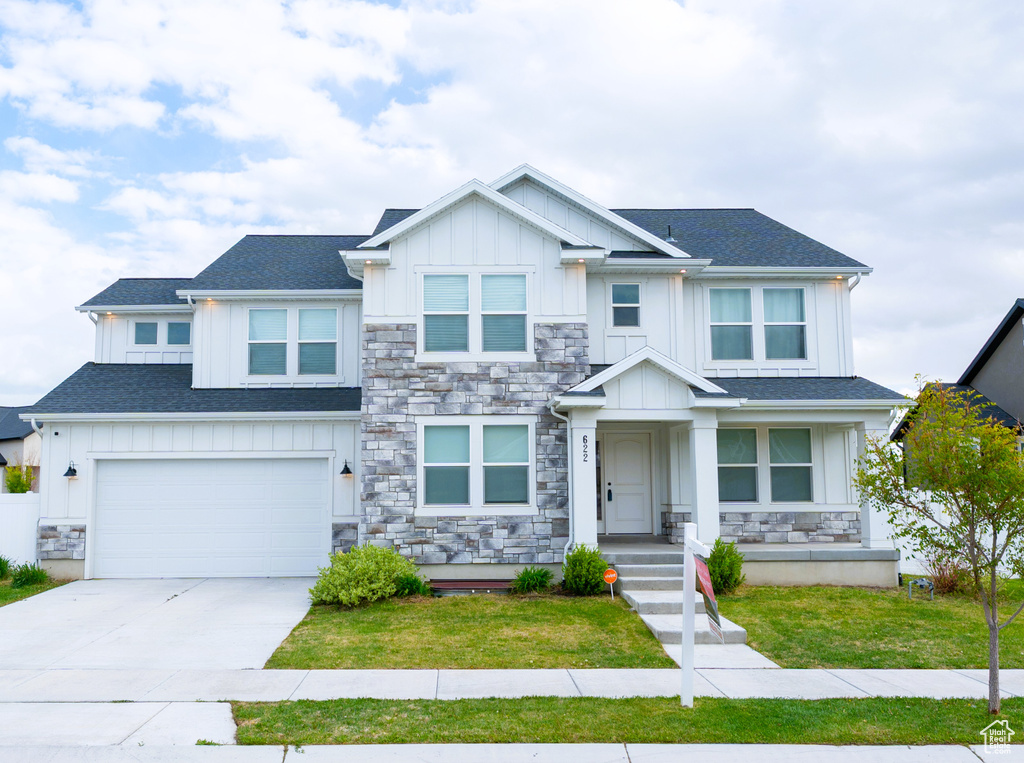 Craftsman inspired home featuring board and batten siding, stone siding, a garage, and concrete driveway