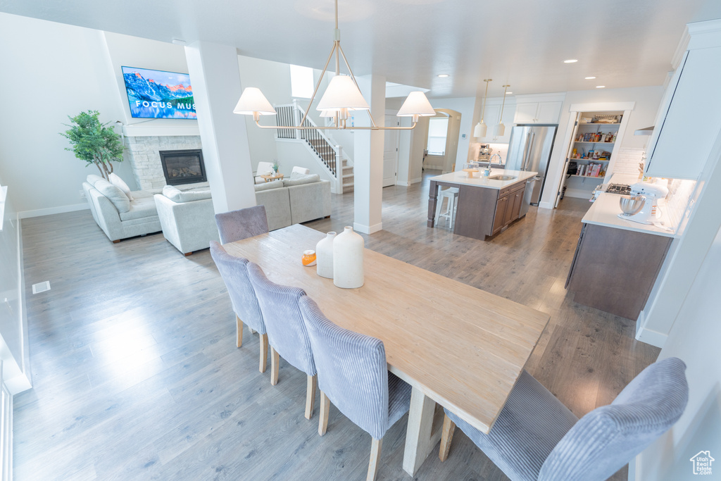 Dining area with a fireplace, baseboards, light wood-style floors, a chandelier, and recessed lighting