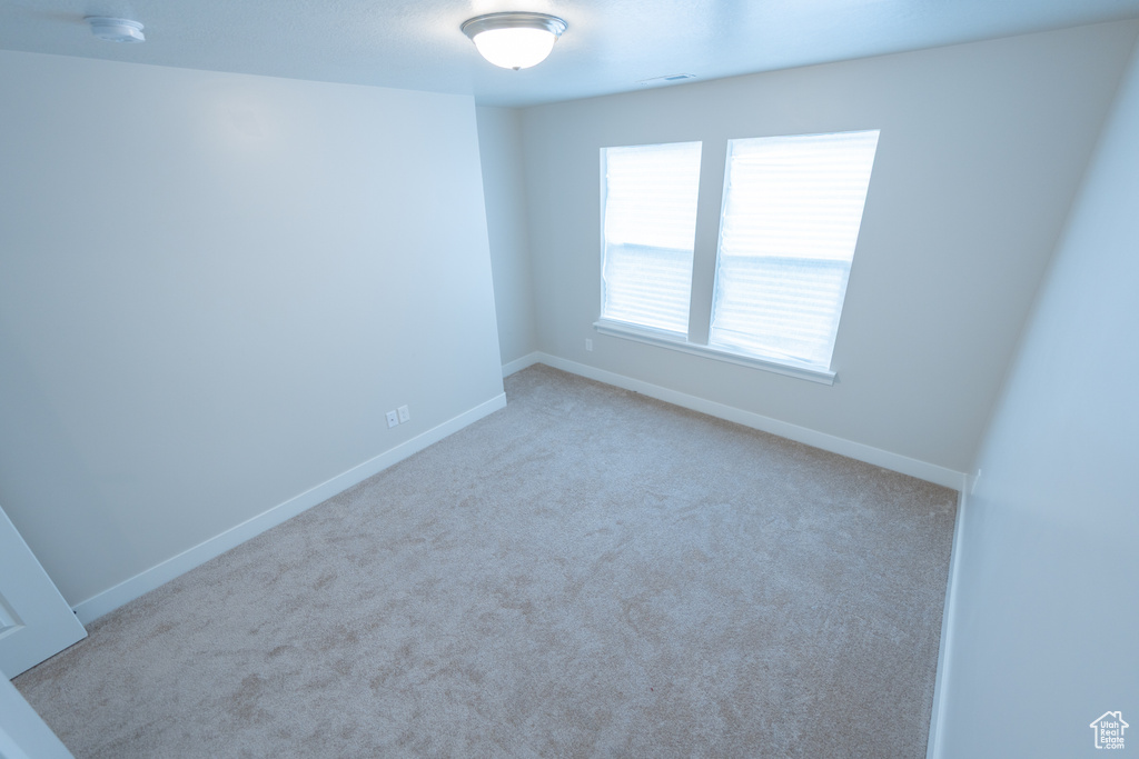Carpeted spare room with baseboards and a smoke detector