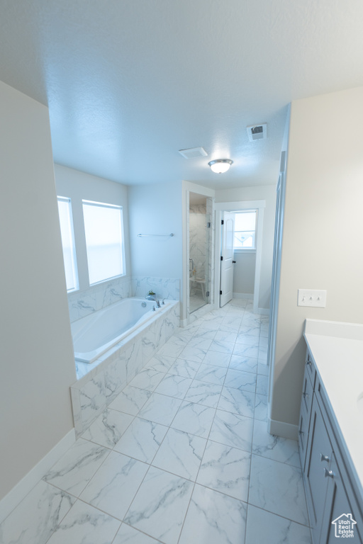 Bathroom with baseboards, vanity, a stall shower, a garden tub, and marble finish flooring