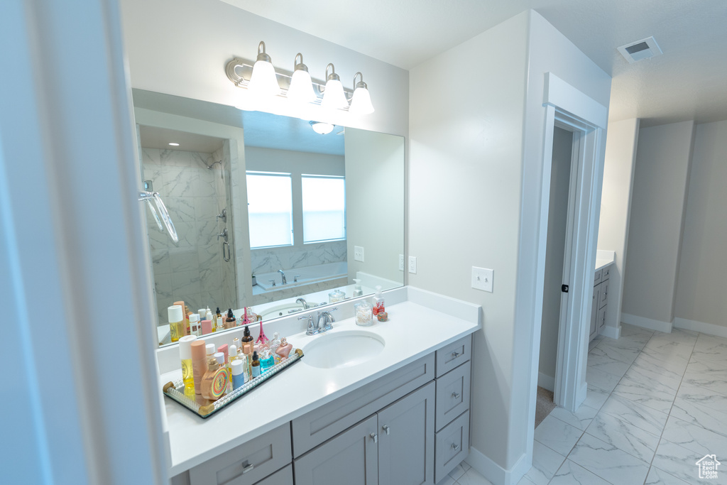 Bathroom featuring marble finish floors, a marble finish shower, vanity, baseboards, and a garden tub