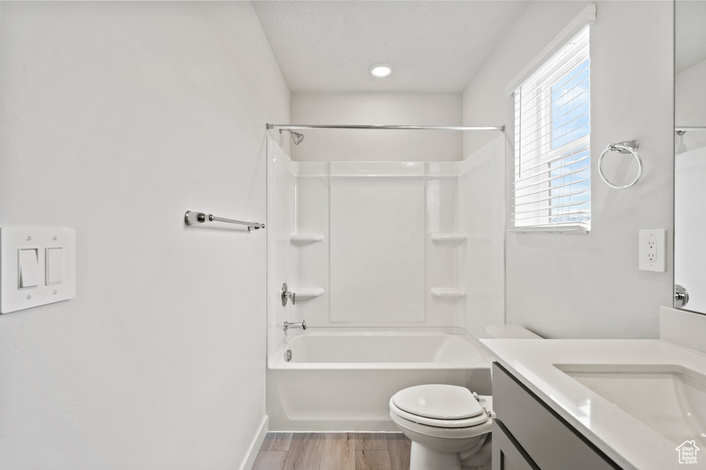 Full bath with wood finished floors, vanity, baseboards, toilet, and shower / tub combination