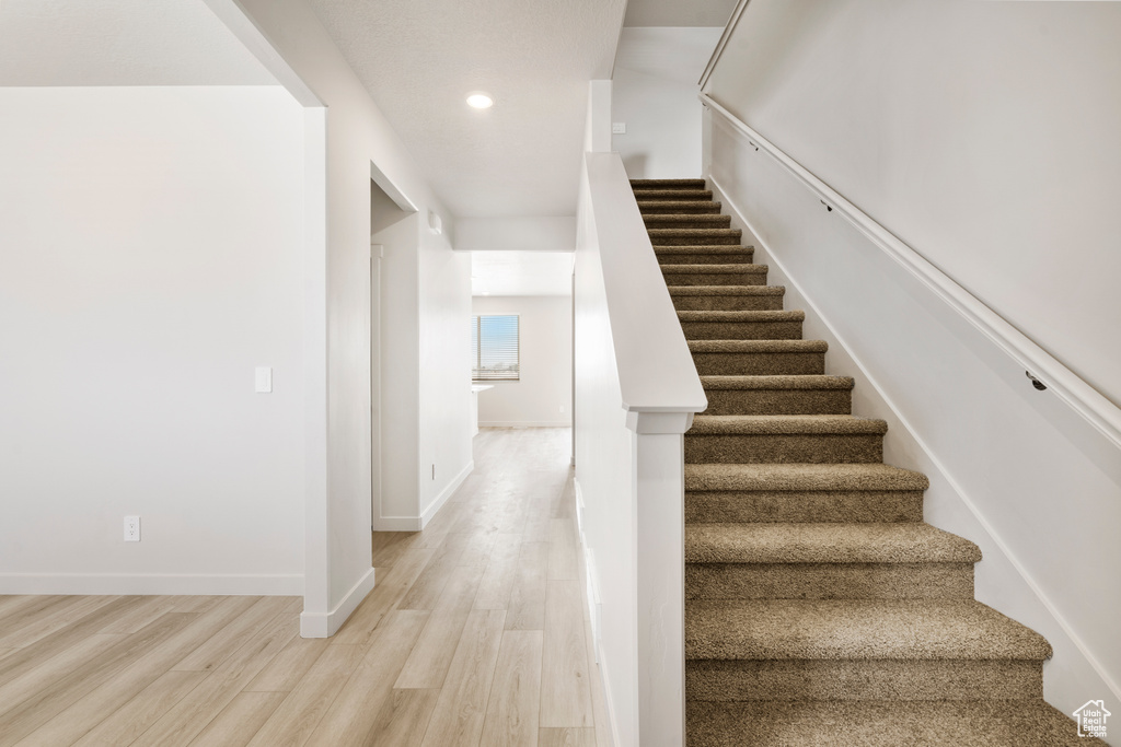 Stairway featuring wood finished floors, recessed lighting, and baseboards