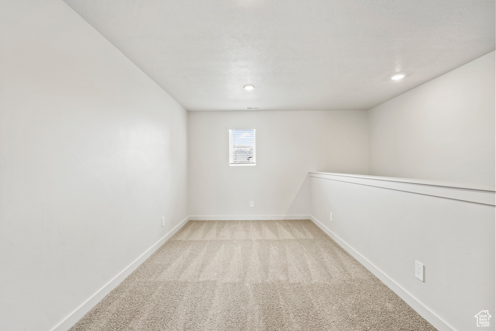 Basement featuring baseboards, light carpet, and recessed lighting