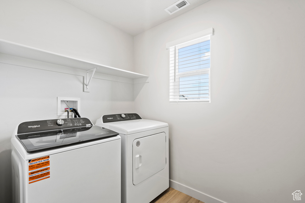 Washroom with light wood finished floors, separate washer and dryer, and baseboards