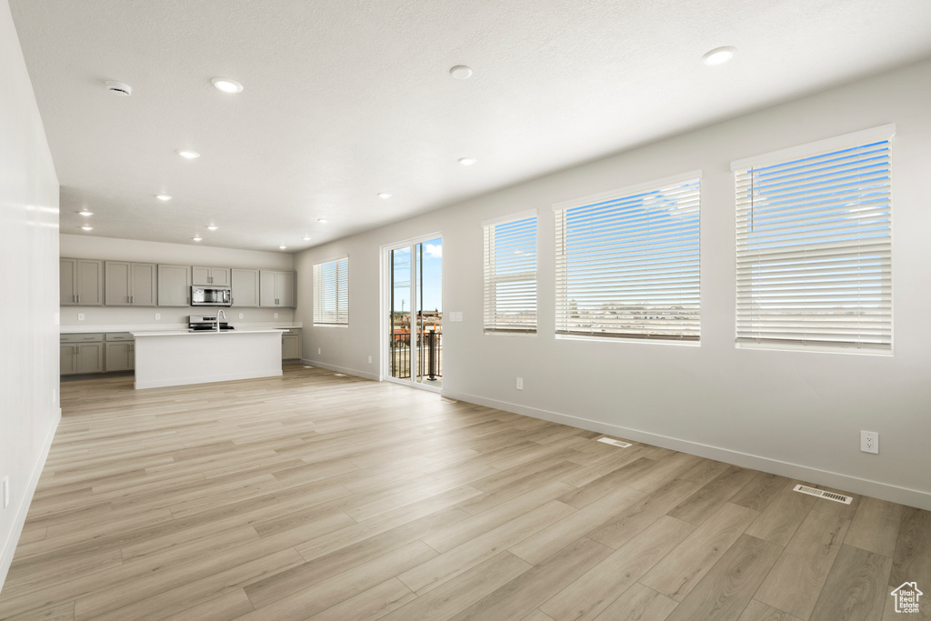 Unfurnished living room with recessed lighting, light wood-type flooring, and baseboards