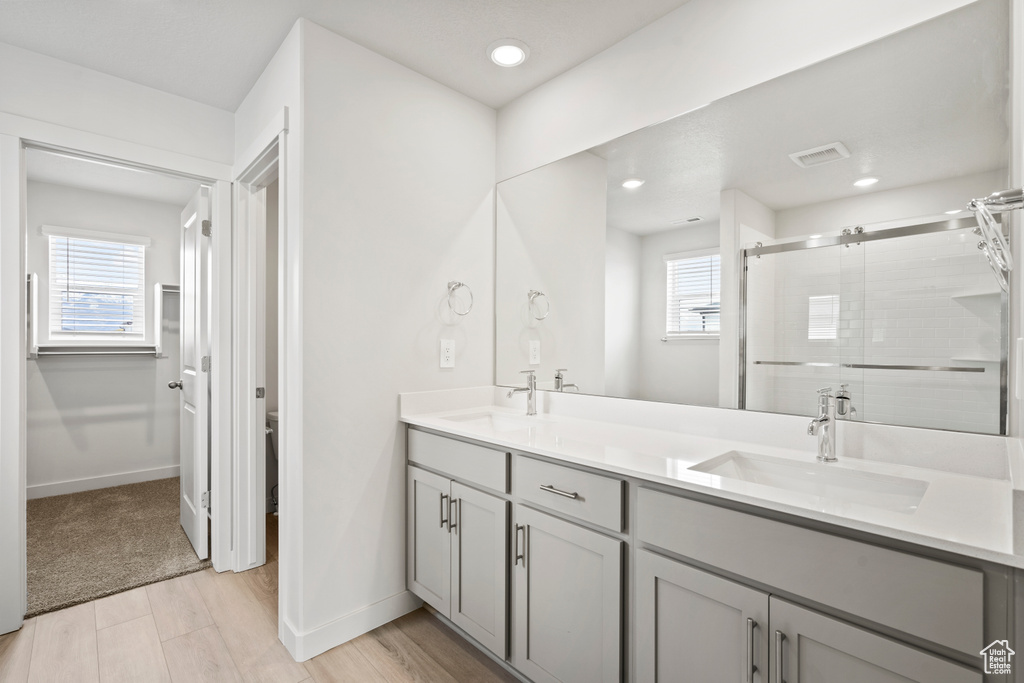 Full bathroom featuring a stall shower, healthy amount of natural light, double vanity, baseboards, and recessed lighting