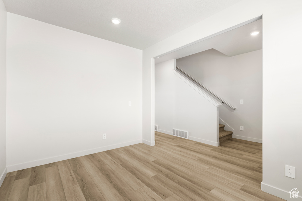 Below grade area with light wood-style flooring, stairs, baseboards, and recessed lighting