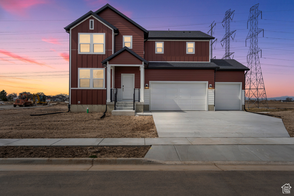View of front of house with board and batten siding, driveway, and an attached garage