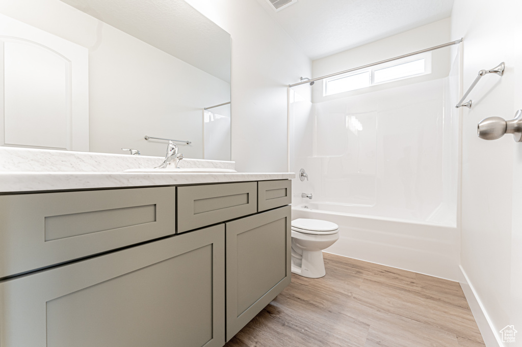 Bathroom with vanity, toilet, visible vents, washtub / shower combination, and wood finished floors