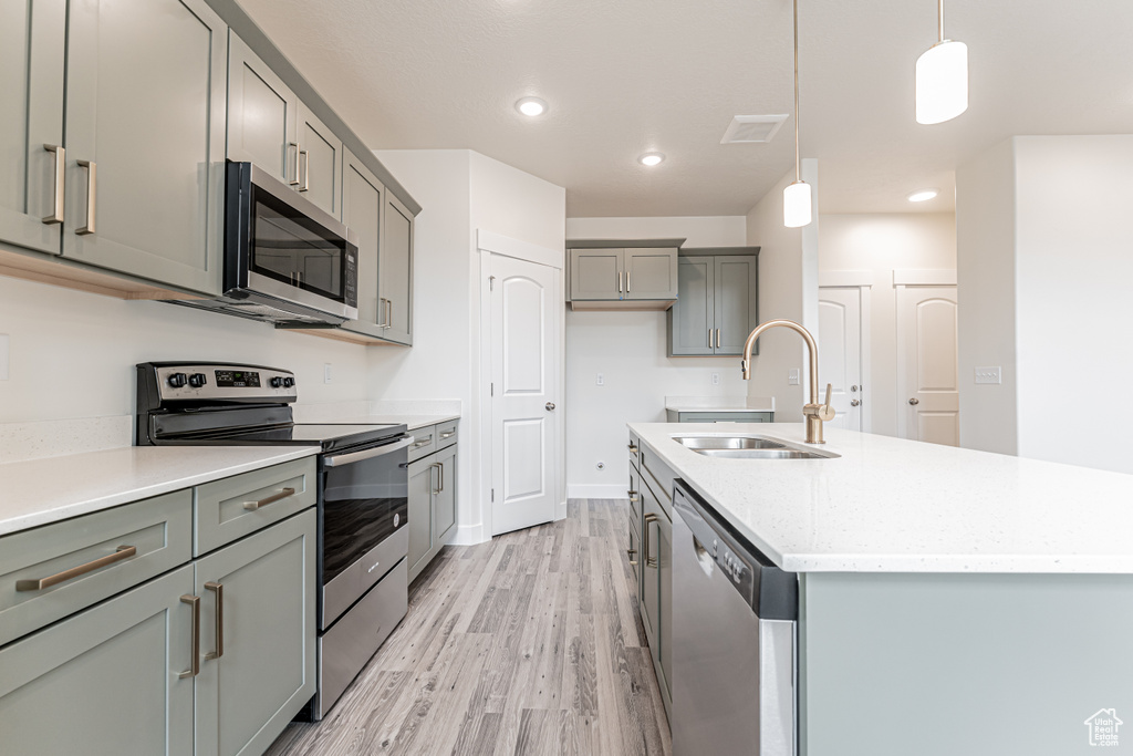 Kitchen with a sink, light wood finished floors, appliances with stainless steel finishes, gray cabinetry, and visible vents