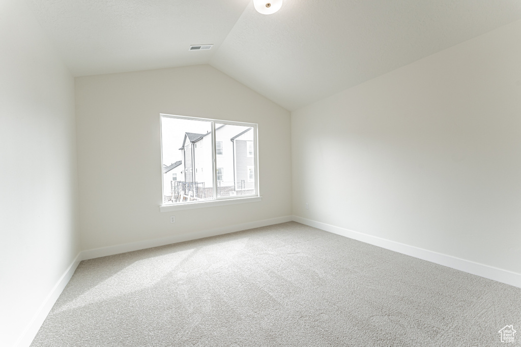 Bonus room featuring baseboards, lofted ceiling, visible vents, and light colored carpet