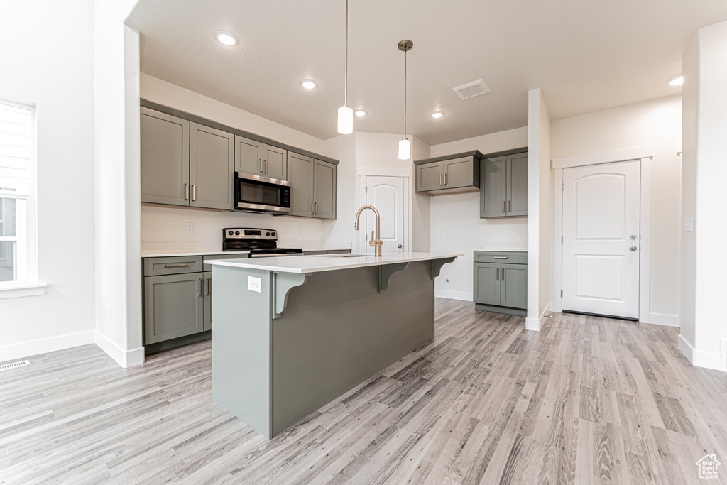 Kitchen with gray cabinetry, light countertops, appliances with stainless steel finishes, and a sink