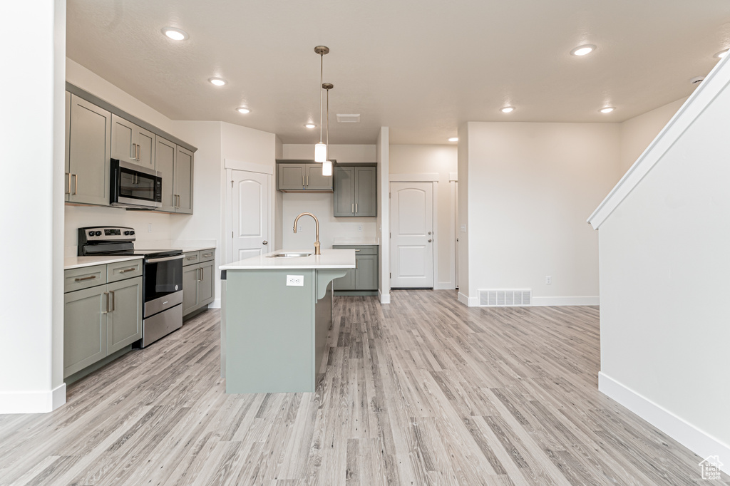 Kitchen with gray cabinets, light countertops, a sink, appliances with stainless steel finishes, and visible vents