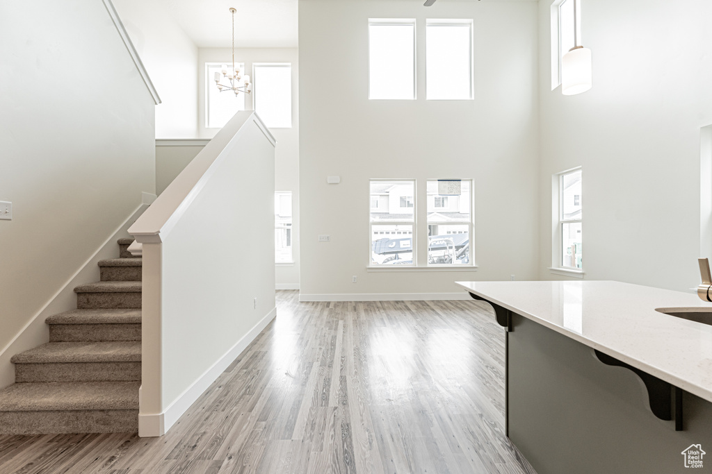 Interior space featuring baseboards, a notable chandelier, light wood-style flooring, and a towering ceiling