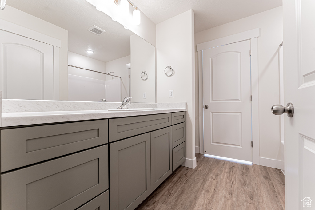 Bathroom with visible vents, wood finished floors, vanity, and walk in shower