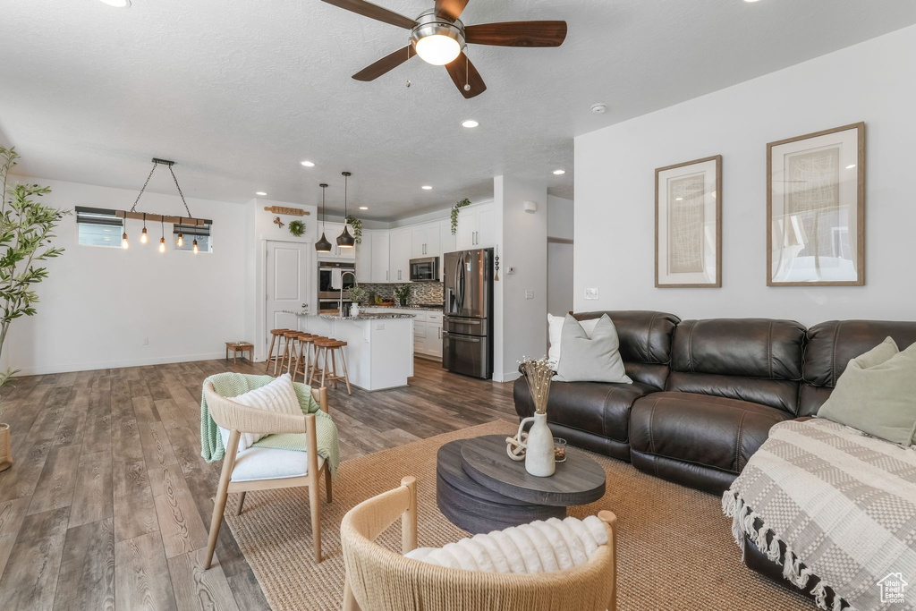 Living area with ceiling fan, dark wood finished floors, and recessed lighting