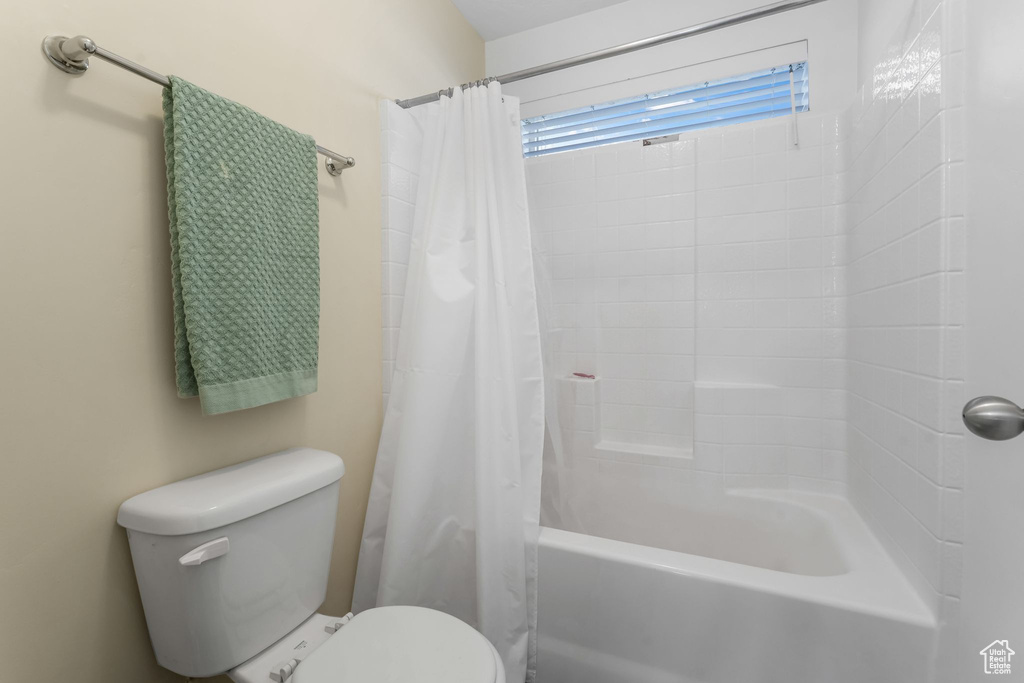 Full bathroom featuring toilet and shower / tub combo with curtain