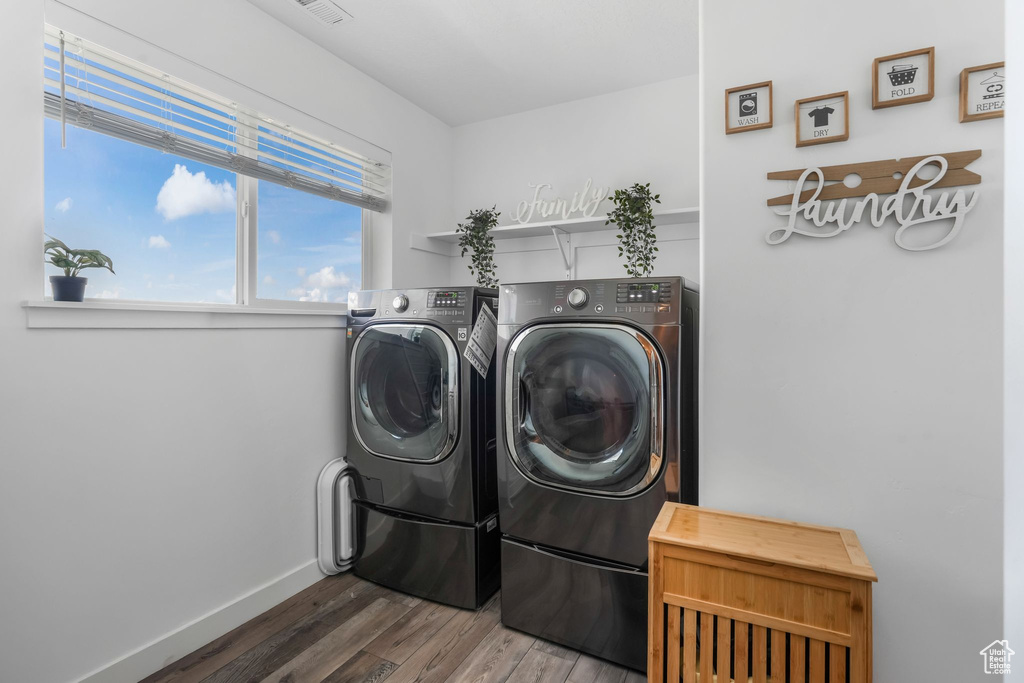 Washroom with independent washer and dryer, wood finished floors, and baseboards