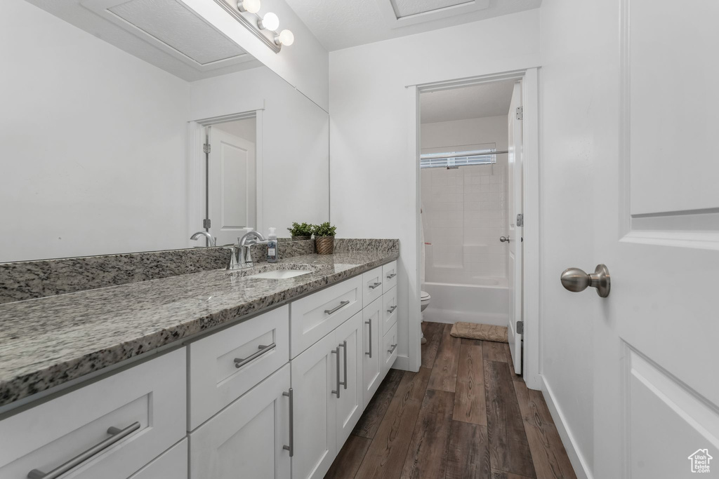 Bathroom featuring toilet, wood finished floors, vanity, and tub / shower combination