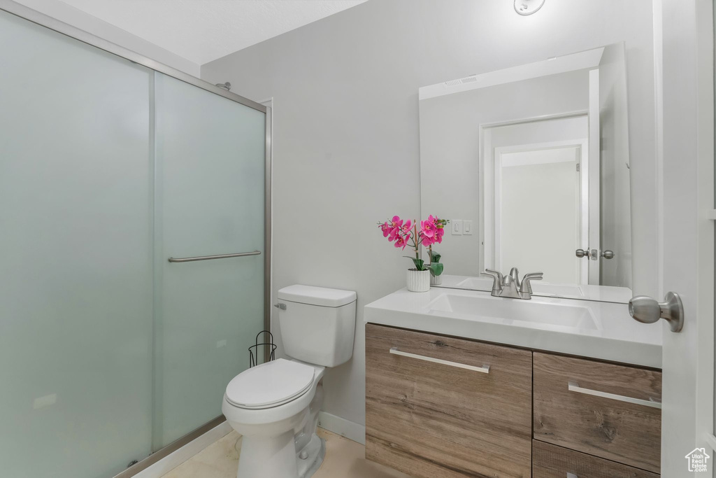 Full bath featuring toilet, vanity, and a shower with shower door