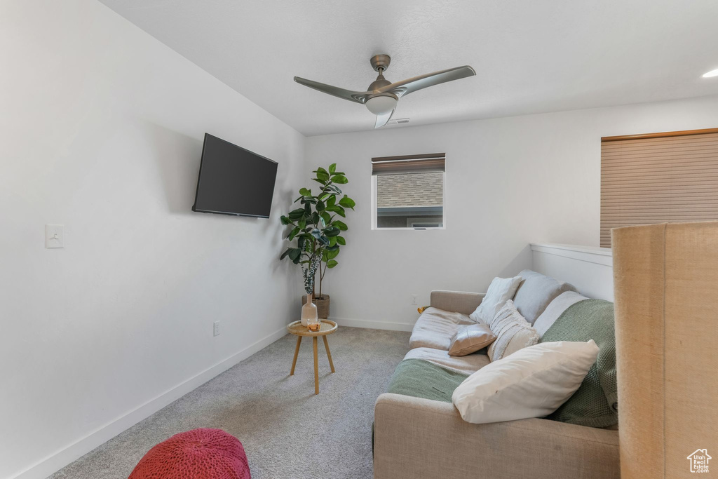 Carpeted living room with ceiling fan and baseboards
