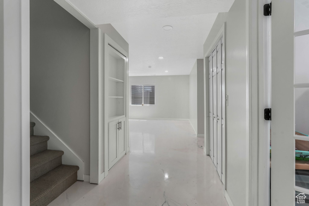Corridor with baseboards, concrete flooring, and stairs