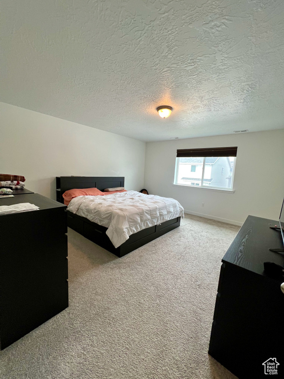 Carpeted bedroom featuring a textured ceiling and baseboards