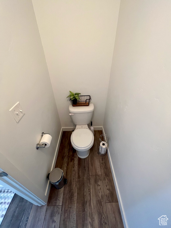 Bathroom featuring wood finished floors, baseboards, and toilet