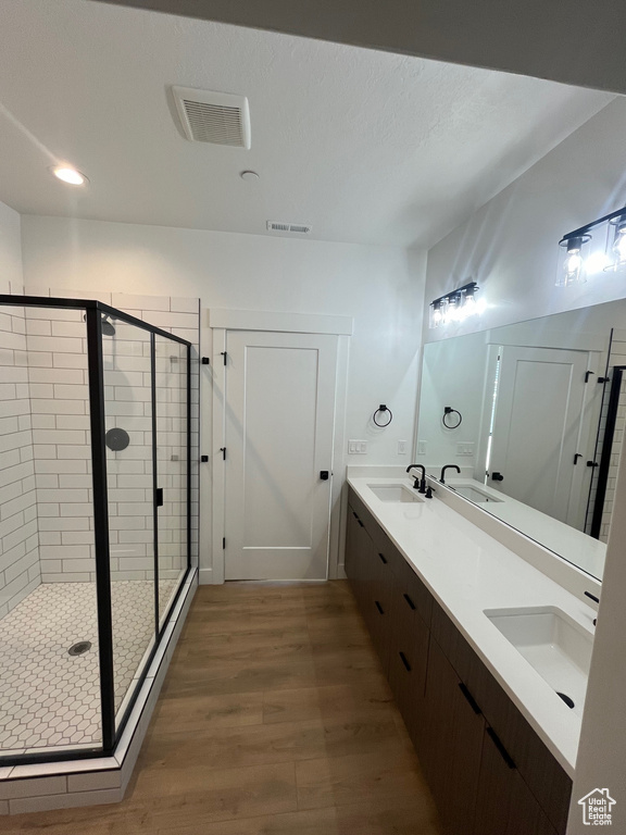 Bathroom with hardwood / wood-style flooring, vanity, and walk in shower