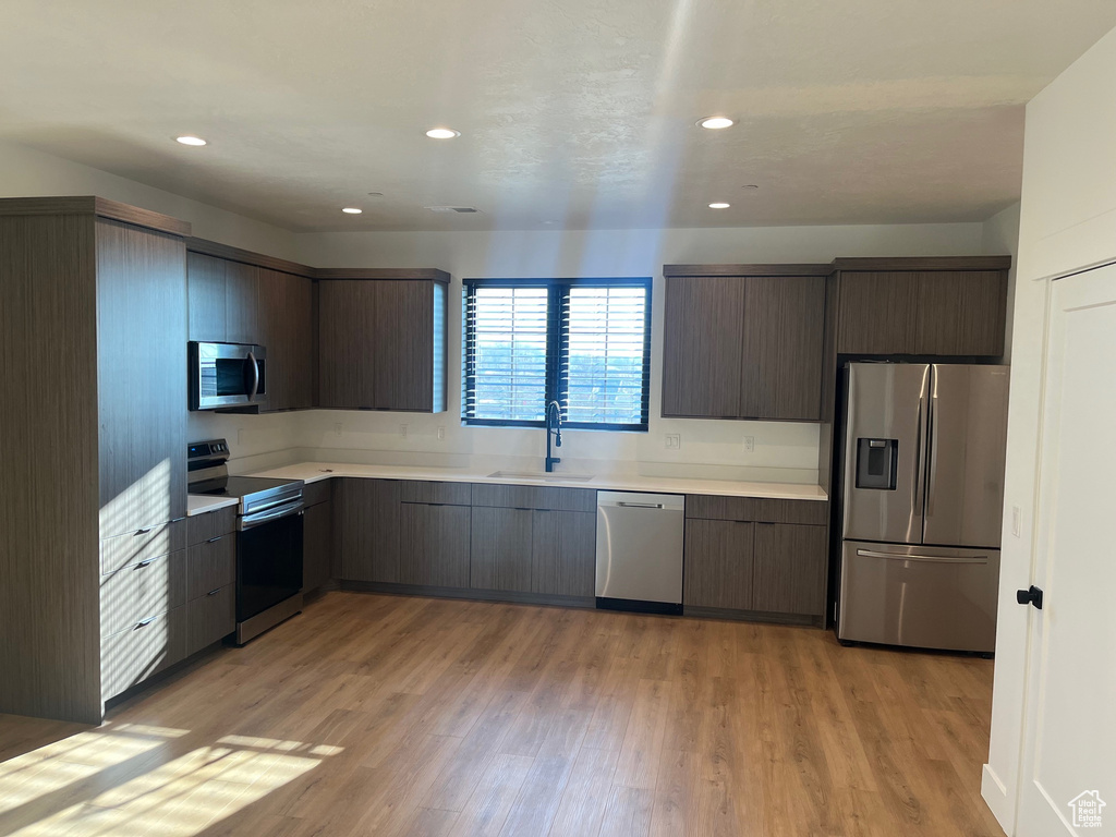 Kitchen with sink, light hardwood / wood-style flooring, and stainless steel appliances