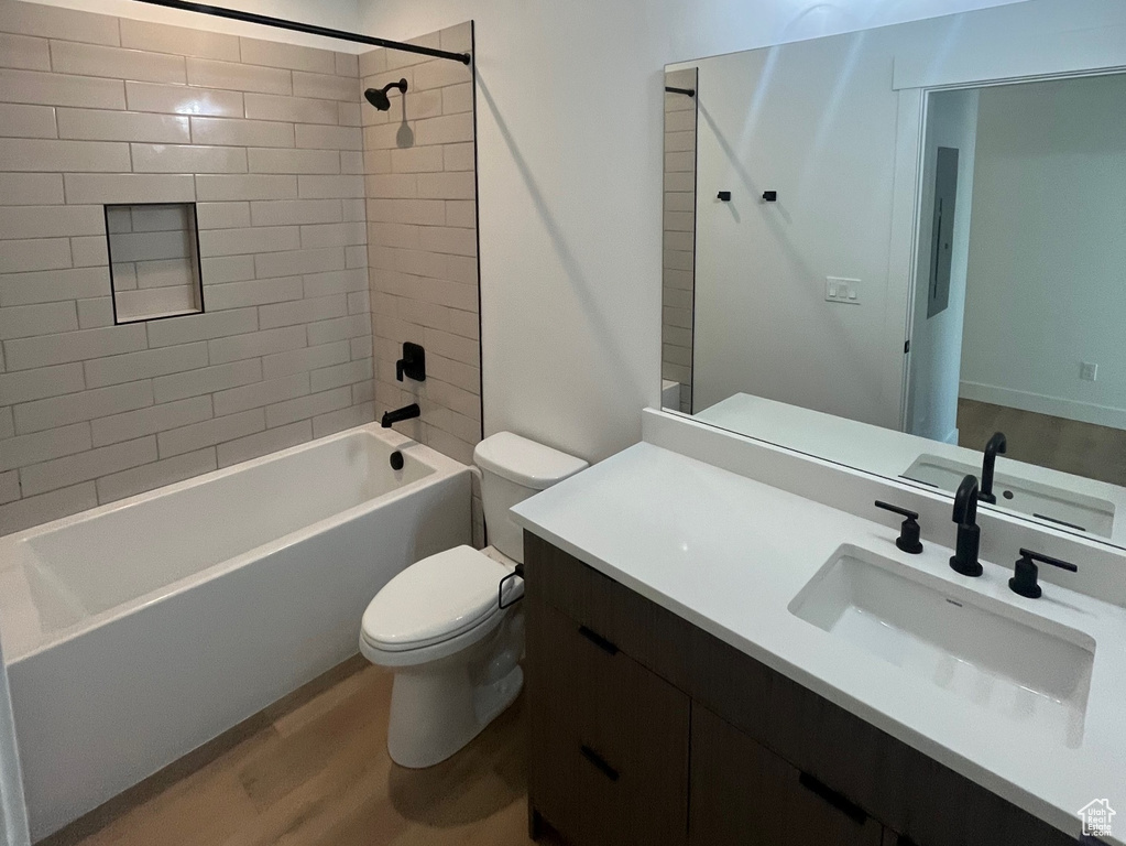 Full bathroom featuring tiled shower / bath, hardwood / wood-style floors, vanity, and toilet