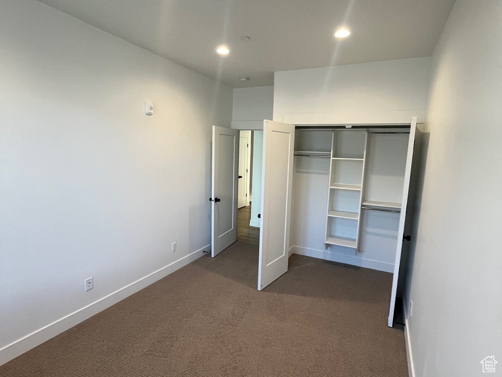 Unfurnished bedroom featuring a closet and dark colored carpet